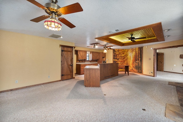 kitchen featuring light carpet, a raised ceiling, kitchen peninsula, and a textured ceiling