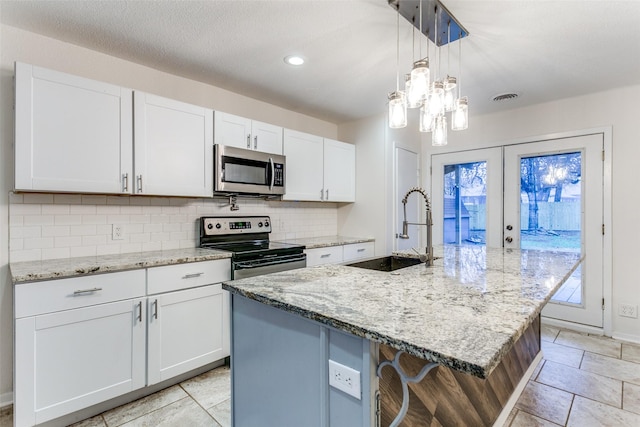 kitchen featuring a kitchen island with sink, white cabinetry, and appliances with stainless steel finishes