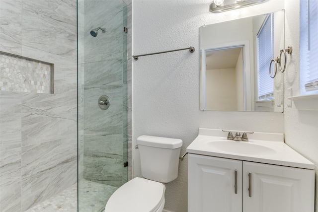 bathroom with tiled shower, vanity, and toilet