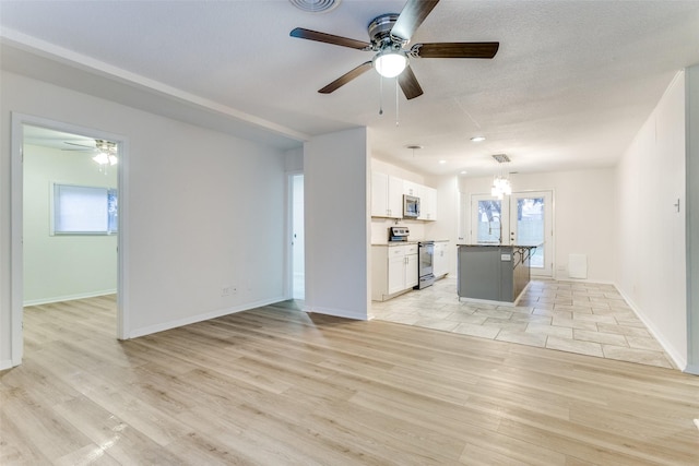 kitchen featuring a kitchen island, appliances with stainless steel finishes, white cabinets, and light wood-type flooring