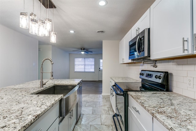 kitchen featuring sink, appliances with stainless steel finishes, white cabinetry, decorative backsplash, and decorative light fixtures