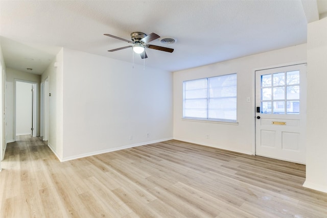 interior space with ceiling fan, a wealth of natural light, a textured ceiling, and light wood-type flooring