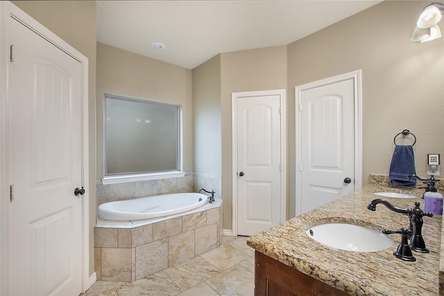 bathroom featuring tiled tub and vanity