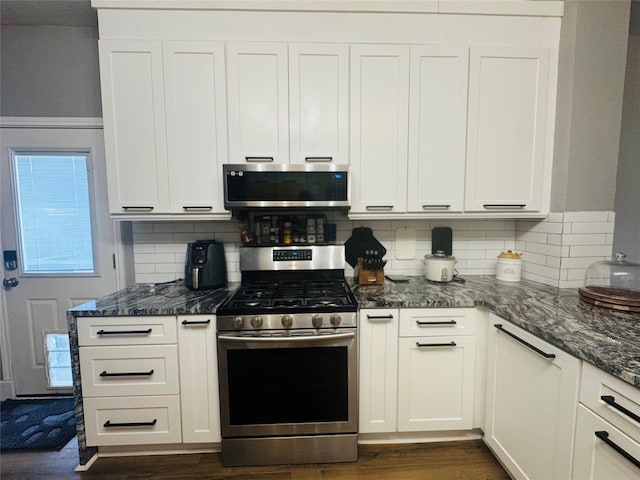 kitchen with stainless steel appliances, dark hardwood / wood-style flooring, dark stone counters, and white cabinets