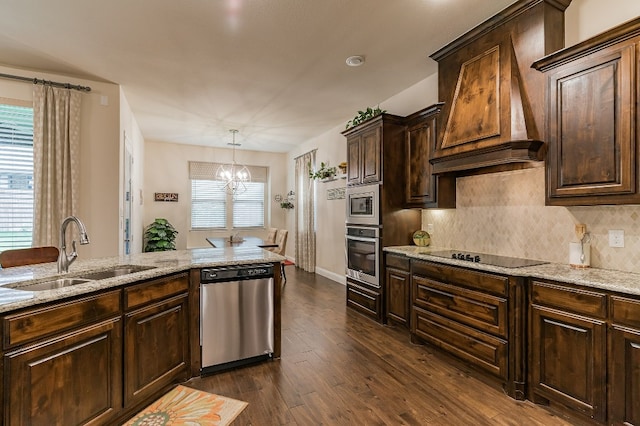 kitchen with premium range hood, appliances with stainless steel finishes, pendant lighting, sink, and dark brown cabinets