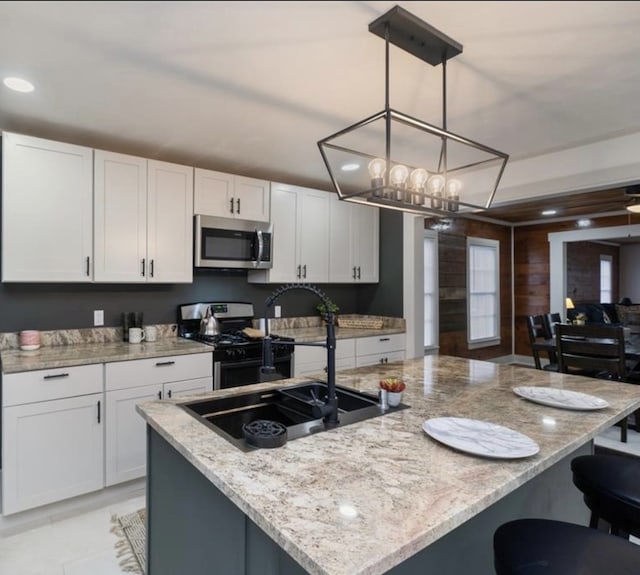 kitchen featuring pendant lighting, stainless steel appliances, light stone counters, and white cabinets