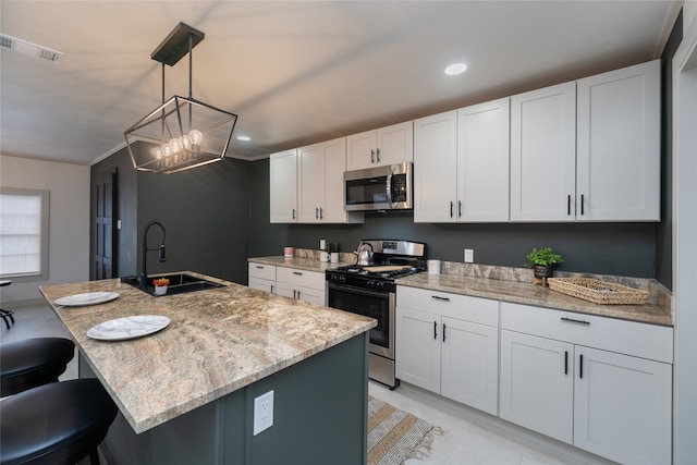 kitchen featuring sink, appliances with stainless steel finishes, a kitchen island with sink, white cabinetry, and hanging light fixtures