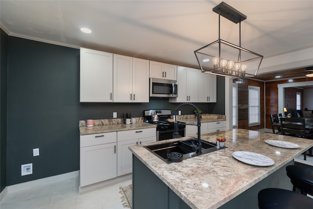 kitchen with white cabinetry, stainless steel appliances, hanging light fixtures, and a center island with sink