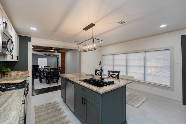 kitchen with a wealth of natural light, an island with sink, sink, hanging light fixtures, and stainless steel appliances