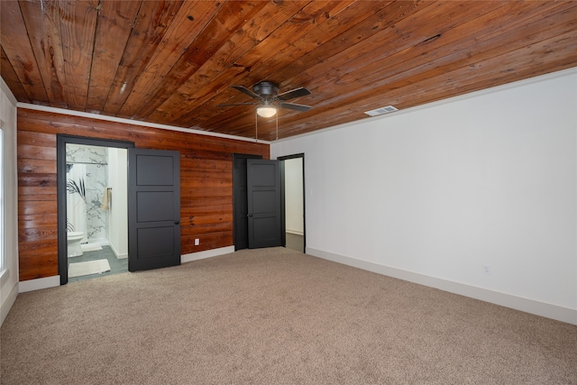 unfurnished bedroom with ensuite bathroom, carpet flooring, wooden ceiling, and wood walls