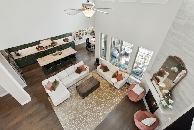 living room with ceiling fan, a towering ceiling, sink, and dark hardwood / wood-style flooring