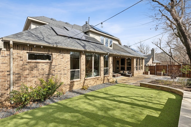 back of house featuring solar panels, outdoor lounge area, a yard, and a patio area