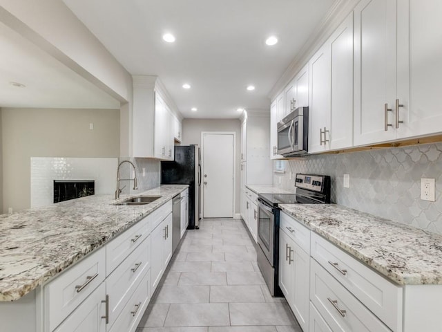 kitchen with appliances with stainless steel finishes, sink, white cabinets, light tile patterned floors, and light stone counters