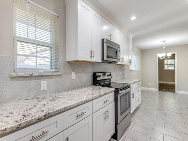 kitchen with white cabinetry, decorative light fixtures, stainless steel appliances, light stone countertops, and decorative backsplash