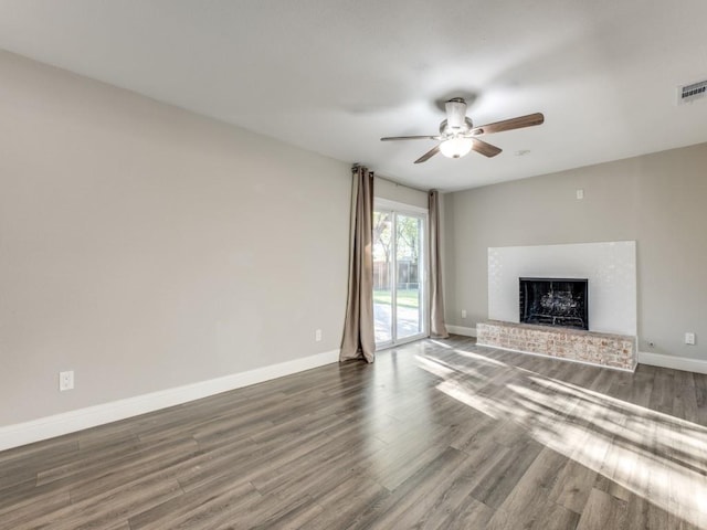 unfurnished living room with dark hardwood / wood-style flooring, a brick fireplace, and ceiling fan