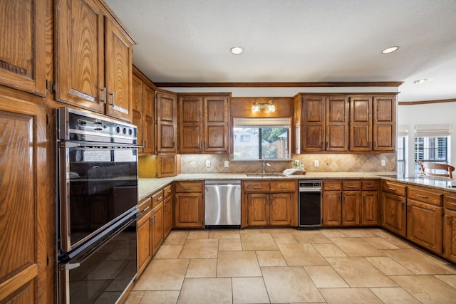 kitchen with sink, double oven, light stone counters, tasteful backsplash, and stainless steel dishwasher