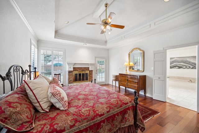 bedroom featuring multiple windows, hardwood / wood-style floors, a tray ceiling, and ornamental molding