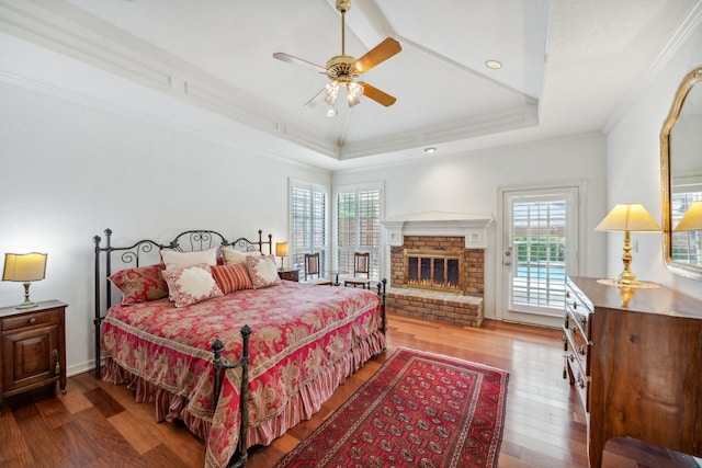 bedroom featuring multiple windows, hardwood / wood-style floors, a tray ceiling, and crown molding