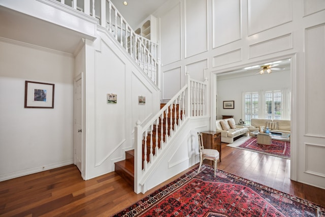 stairs featuring a high ceiling, ornamental molding, and hardwood / wood-style floors