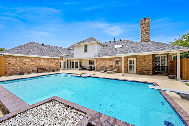 view of swimming pool with a patio area and a diving board