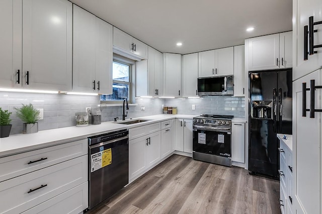 kitchen with sink, hardwood / wood-style floors, white cabinets, and black appliances