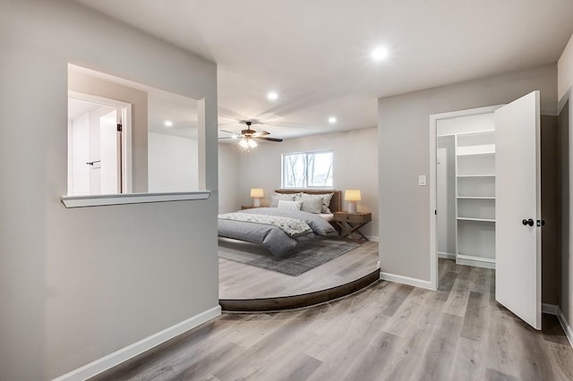 bedroom with a spacious closet, light hardwood / wood-style floors, and ceiling fan