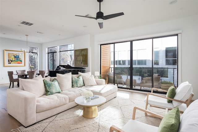 living room featuring hardwood / wood-style flooring, ceiling fan with notable chandelier, and a wealth of natural light