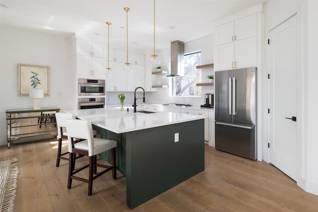 kitchen featuring sink, island range hood, a center island with sink, appliances with stainless steel finishes, and white cabinets