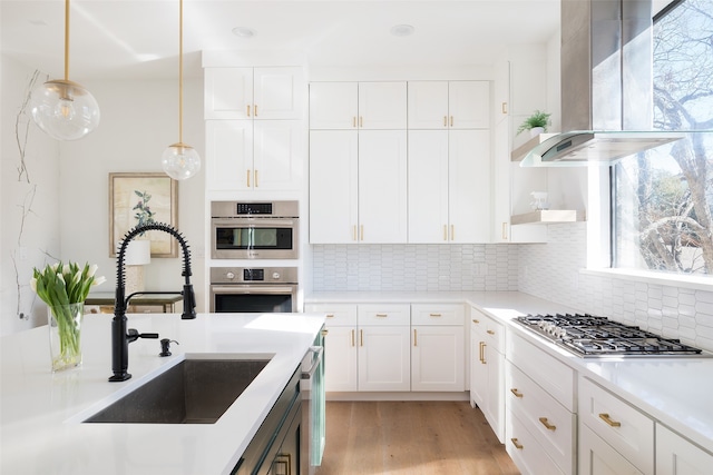 kitchen with sink, decorative light fixtures, exhaust hood, and white cabinets