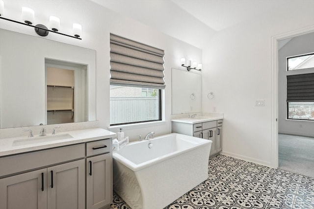 bathroom featuring vanity, a tub, a healthy amount of sunlight, and tile patterned floors