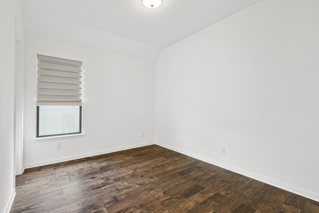 empty room featuring vaulted ceiling and dark hardwood / wood-style flooring