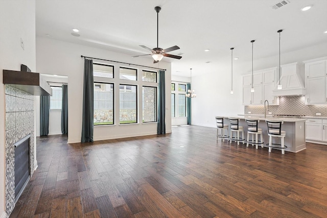 unfurnished living room featuring dark hardwood / wood-style floors, a fireplace, and ceiling fan with notable chandelier