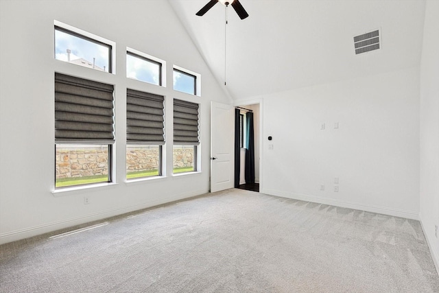 carpeted spare room with ceiling fan and high vaulted ceiling