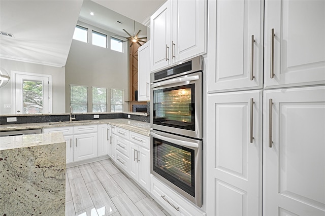 kitchen with white cabinetry, stainless steel appliances, and light stone counters