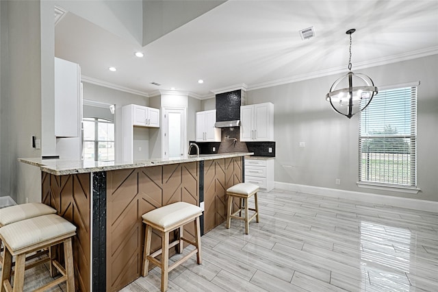 kitchen with decorative light fixtures, white cabinetry, a kitchen breakfast bar, decorative backsplash, and kitchen peninsula