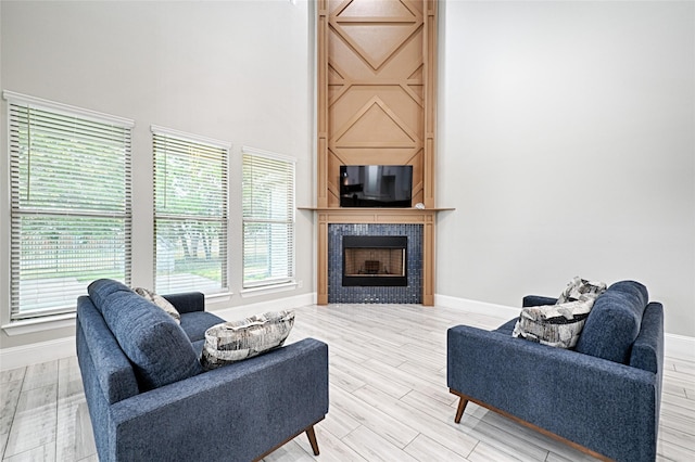 living room with wood-type flooring, a fireplace, and a high ceiling