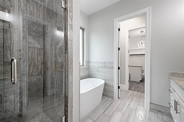 bathroom with vanity, separate shower and tub, and tile walls