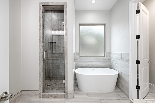 bathroom with separate shower and tub and tile walls