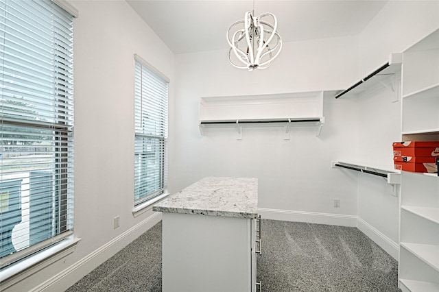 walk in closet with a chandelier, a wall unit AC, and dark colored carpet