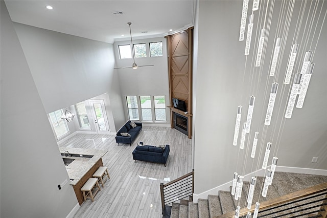 living room with light hardwood / wood-style flooring, ceiling fan, and a high ceiling