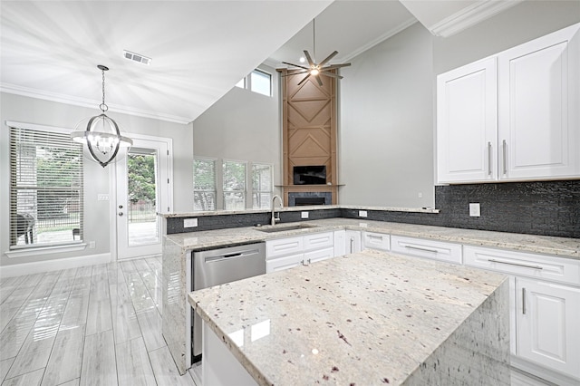 kitchen with sink, white cabinetry, hanging light fixtures, light stone countertops, and kitchen peninsula