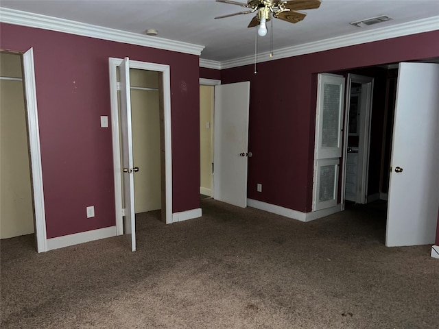 unfurnished bedroom featuring ceiling fan, crown molding, carpet floors, and multiple closets