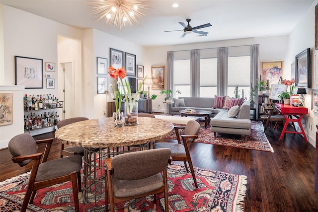 dining room with ceiling fan with notable chandelier and dark hardwood / wood-style floors