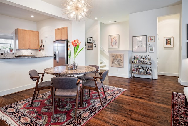 dining area with a notable chandelier, dark wood-type flooring, and sink