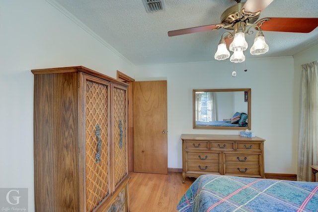 bedroom with ceiling fan, ornamental molding, light hardwood / wood-style floors, and a textured ceiling