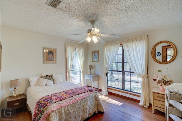 bedroom featuring ceiling fan, hardwood / wood-style flooring, and a textured ceiling