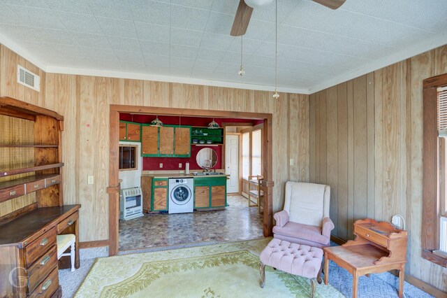 sitting room featuring sink, ceiling fan, wooden walls, plenty of natural light, and washer / clothes dryer