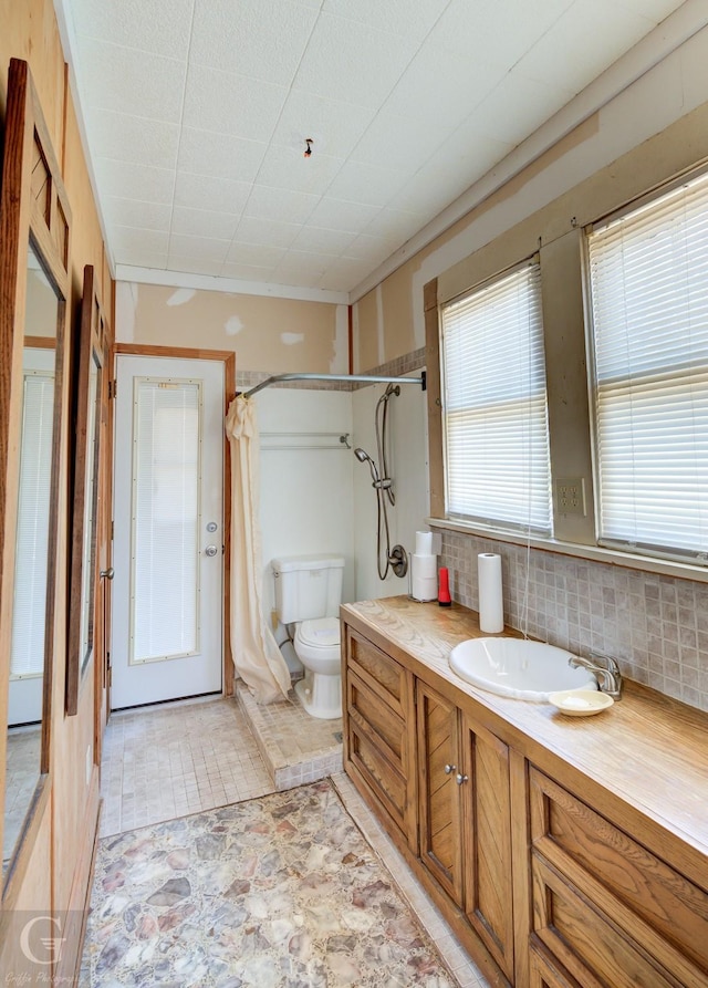 bathroom featuring vanity, toilet, a shower with shower curtain, and backsplash