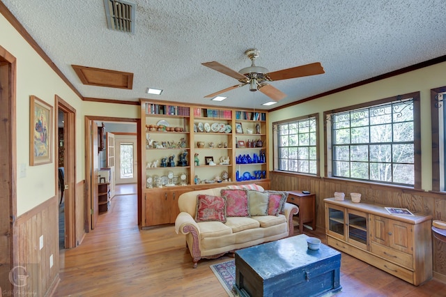 living room with ornamental molding, light hardwood / wood-style floors, and a textured ceiling