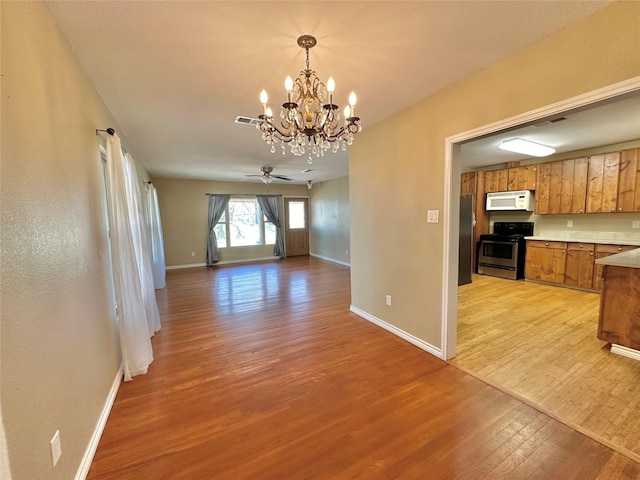 interior space featuring ceiling fan with notable chandelier and light wood-type flooring